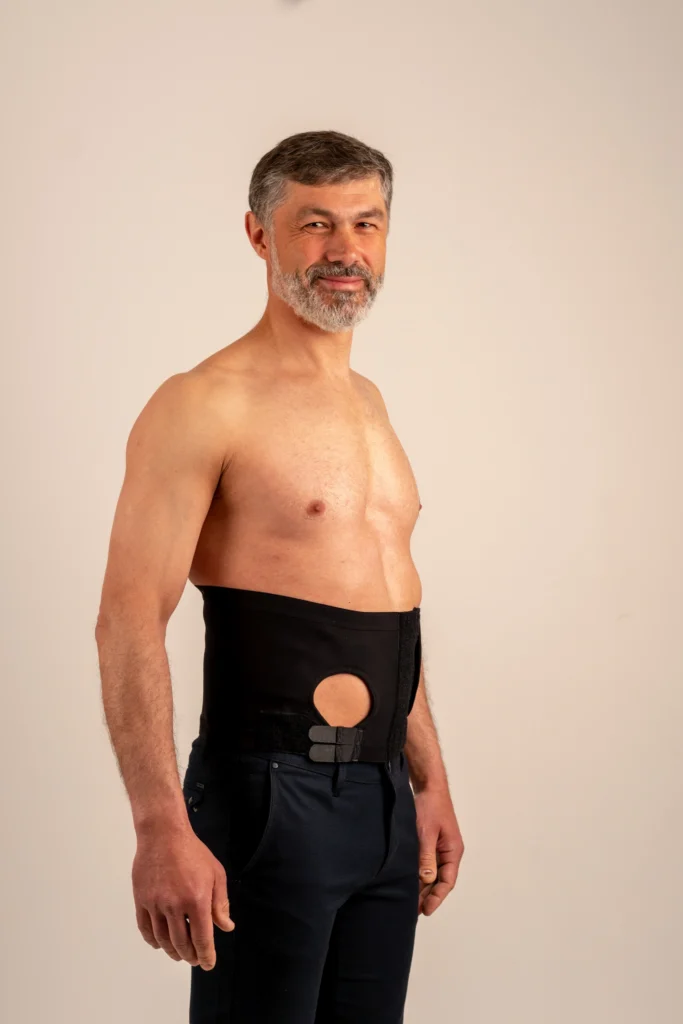 Man wearing a black ostomy hernia support belt with a pouch opening